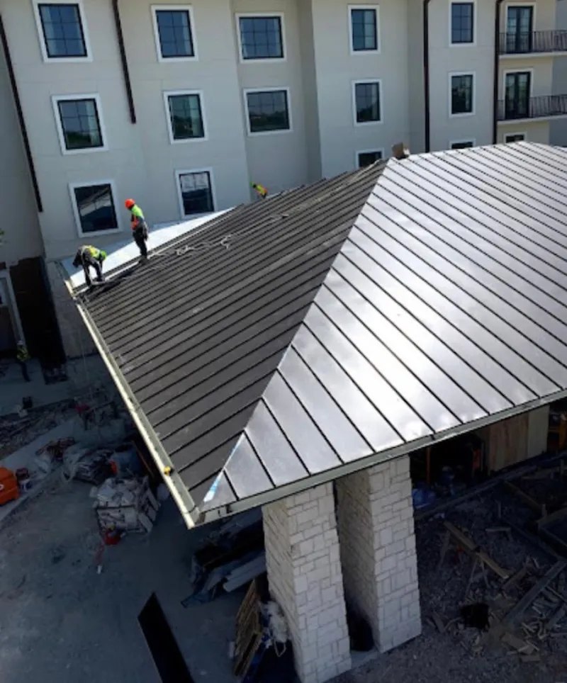 Crew installing standing seam metal roof panels on a commercial project in Eliot